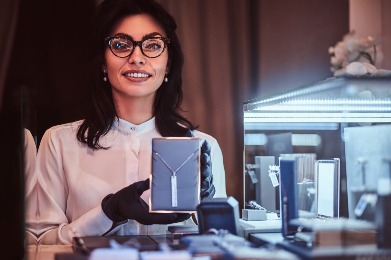 A woman in a jewellery store tries to deliver a luxury customer service experience to the buyers.