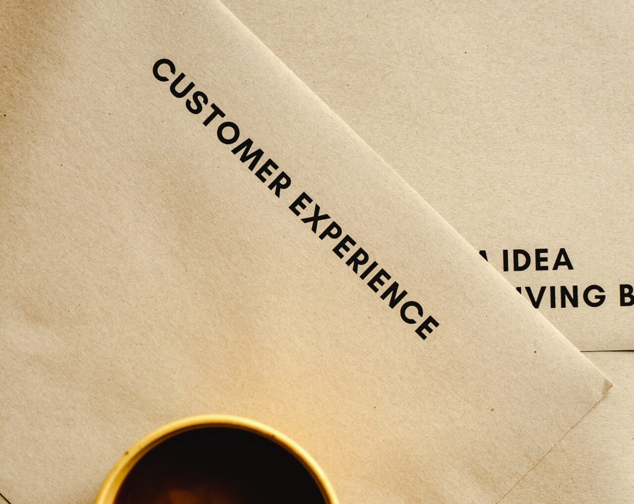 A cup of coffee and a paper are on the table, signalizing the importance of success in EX and CX.