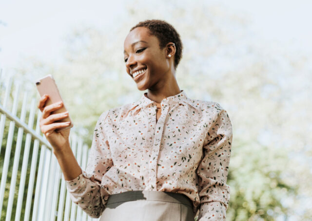 A woman uses her phone to shop online, confirming adults will prefer digital channels post-pandemic.