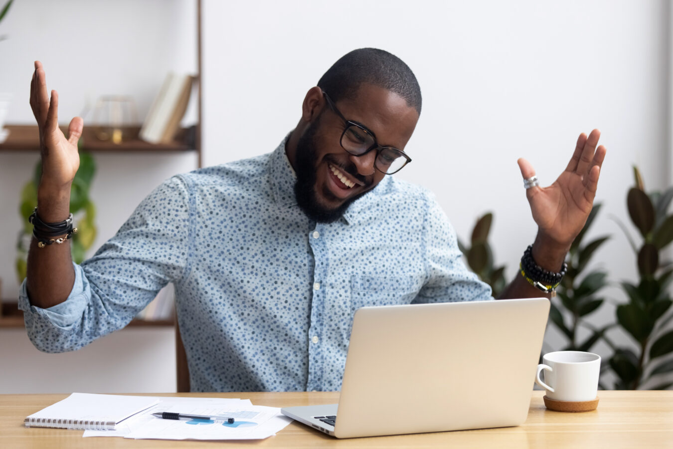 A man at his desk is happy for receiving an employee reward.
