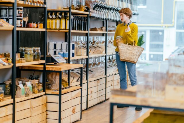 A conscious consumer shops in the store with a bag full of green vegetables.