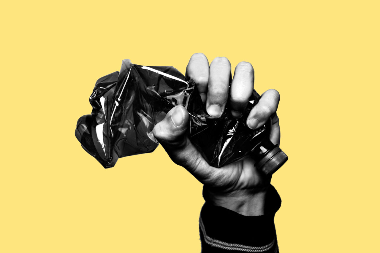 An image showing a had smashing a plastic bottle as a message of sustainability promises companies give to customers.