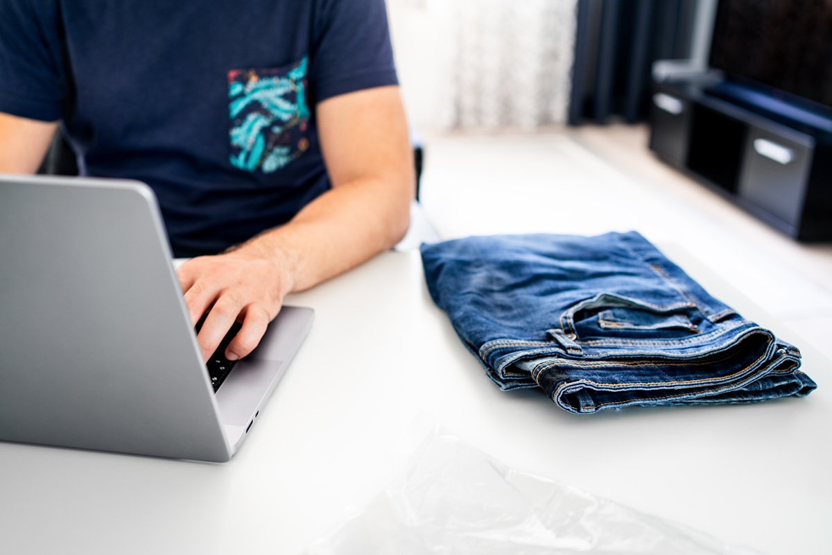 Person trying to return jeans online, while typing on a laptop.