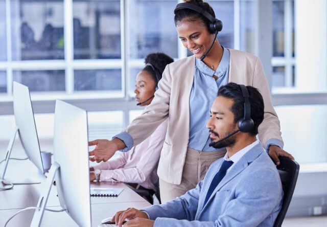 Two people in contact centre working and talking.