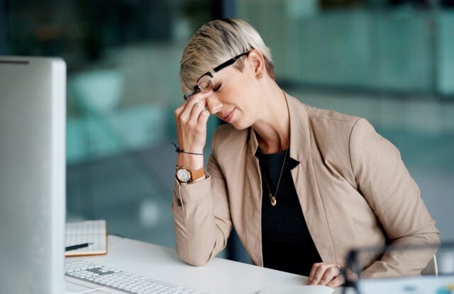 Woman sitting in front of a laptop, tired and unhappy.