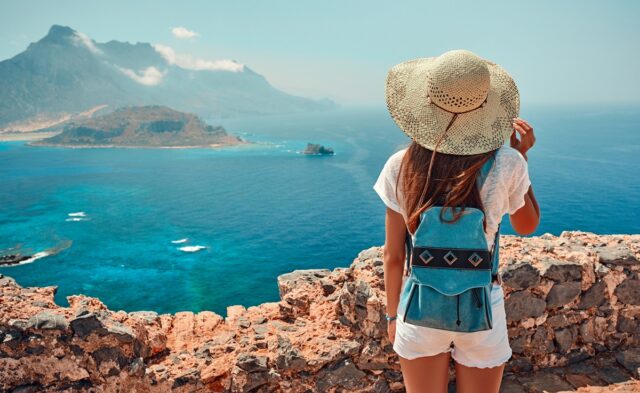 A woman travelling, looking at a beautiful view of the sea.
