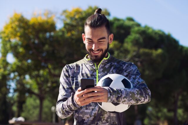 Football fan using his phone and smiling.